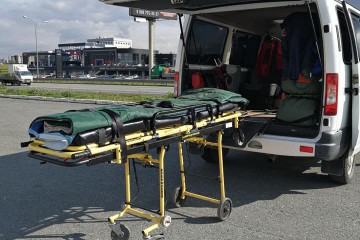 Loaded stretcher beside a transport van waiting in a parking area